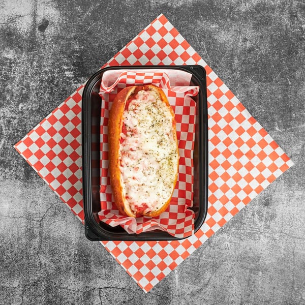 Trent's Pizzeria's cheesy pizza sub, topped with herbs, in a black container on red and white checkered paper.