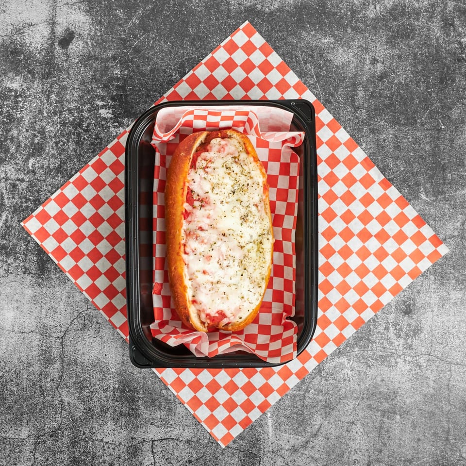 Trent's Pizzeria's cheesy pizza sub, topped with herbs, in a black container on red and white checkered paper.