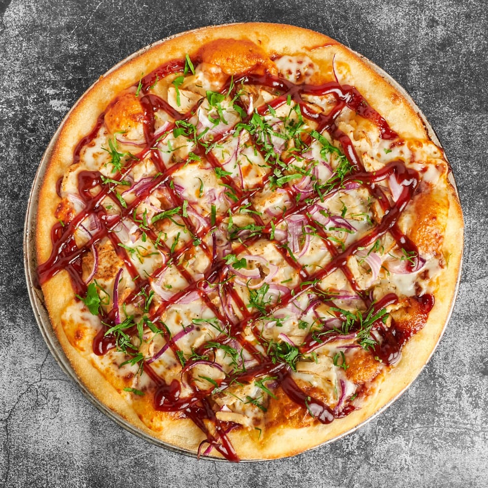 Trent's Pizzeria BBQ chicken pizza with red onions, cilantro, and a crisscross of BBQ sauce.