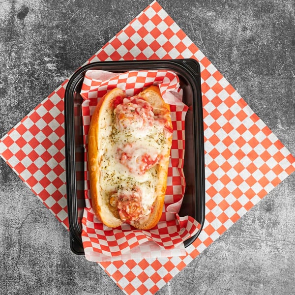 Trent's Pizzeria meatball sub with melted cheese and sauce in a black container on checkered paper.