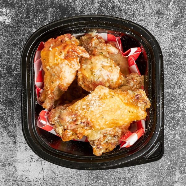 Trent's Pizzeria garlic parmesan wings in a black container with red and white checkered paper.